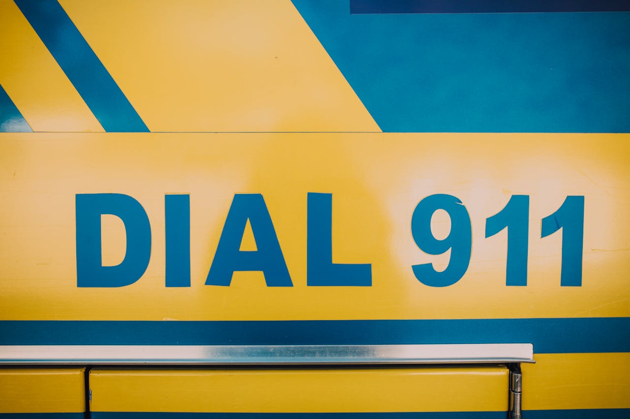 Close-up of Dial 911 emergency sign on a vehicle with bold yellow and blue colors.